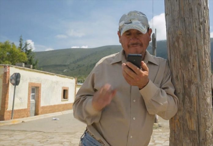 A man in a rural area checks his cell phone.
