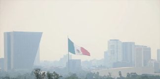 A flag flies above Chapultepec on a smoggy day.