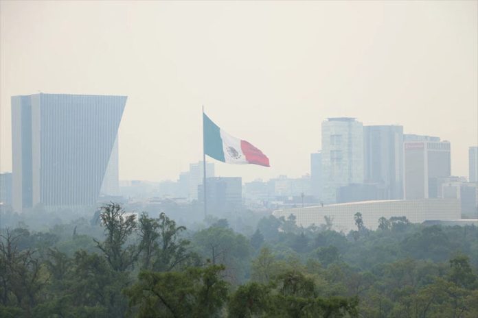 A flag flies above Chapultepec on a smoggy day.