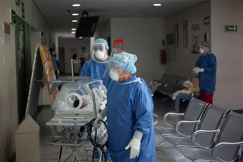 Workers in the COVID area of a Mexico City hospital transport an infant.