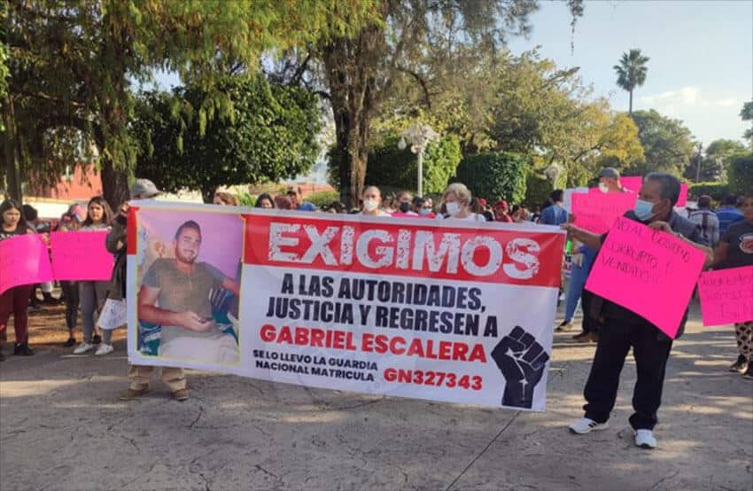 Protesters with a sign demanding justice and the return of Gabriel Escalera, who was recorded being taken away by a National Guard vehicle.