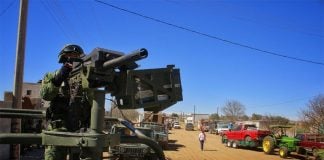A soldier stands guard while Palma Alta residents pack up their belongings.