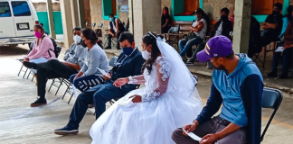 The bride and the groom wait for their turn to be vaccinated.