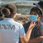 An INM agent speaks with migrants near the Mexico-US border.