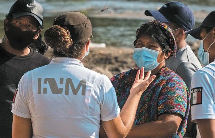 An INM agent speaks with migrants near the Mexico-US border.