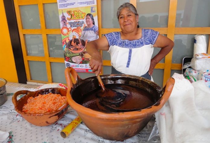 A woman stirs a pot of mole at a fair in San Lucas Atzala