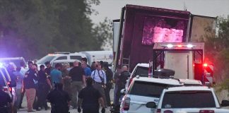 Police and emergency personnel at work with the open trailer in the background.