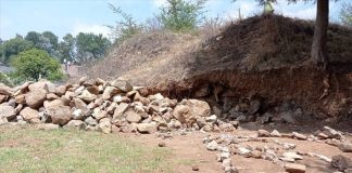 A small, overgrown pyramid with some rocks removed, apparently by humans