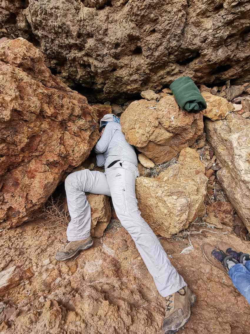 An intrepid biologist squeezes among the rocks to check a nest.