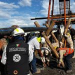 Rescue workers outside El Pinabete mine, propping up a water pipe with logs, while a government Sinaproc official looks on.