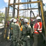 Rescue workers gather around the entrance to the mine on Sunday as water is pumped out.