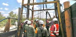 Rescue workers gather around the entrance to the mine on Sunday as water is pumped out.
