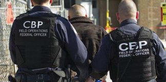 US border patrol officials taking a migrant into custody