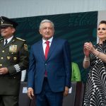 Defense Minister Luis Cresencio Sandoval, President López Obrador and his wife Beatriz Gutiérrez Müller stand on stage after the president's speech.