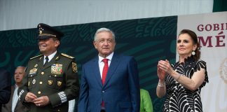 Defense Minister Luis Cresencio Sandoval, President López Obrador and his wife Beatriz Gutiérrez Müller stand on stage after the president's speech.