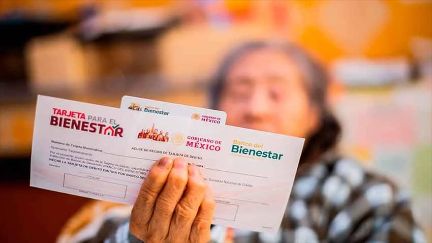 An elderly woman displays her pension card and Welfare Ministry paperwork for the camera