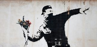 “Love is in the Air,” a 2003 stencil mural in the West Bank, territory that is claimed by both Israel and Palestine.