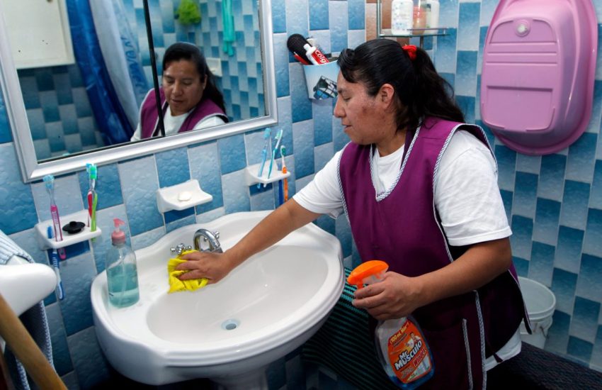 A woman cleaning a bathroom sink.