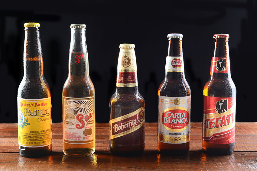 Commonly exported varieties of Mexican beer including Tecate, Sol and Pacífico on a dark background.