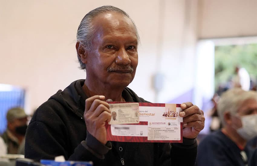 Un adulto mayor mexicano posando con su tarjeta de pensión