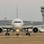 An aerplane on a runway with the airport in the background.
