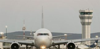 An aerplane on a runway with the airport in the background.