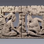 A lord and his companion observe a small supernatural creature seated between them in this intricately carved backrest for a throne.
