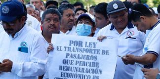 "By law, the transport of passengers for economic remuneration is public service," reads a sign held by taxi drivers who protested outside the federal courts in Cancún on Wednesday.