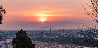 Smoggy sunrise over a mountain with the city sprawled belong in the foreground.