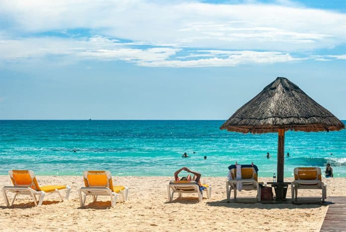 Tourists swim and lounge on a Cancún beach.