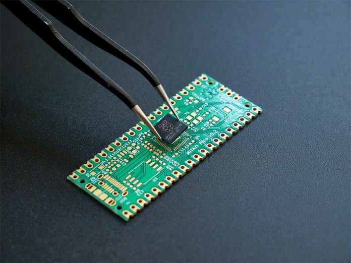 Tweezers hold a surface mounted semiconductor device over a printed circuit board, as if about to mount the device on the board.