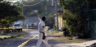 A forensic worker cordons off the scene of a double homicide in Morelos, in December 2021.