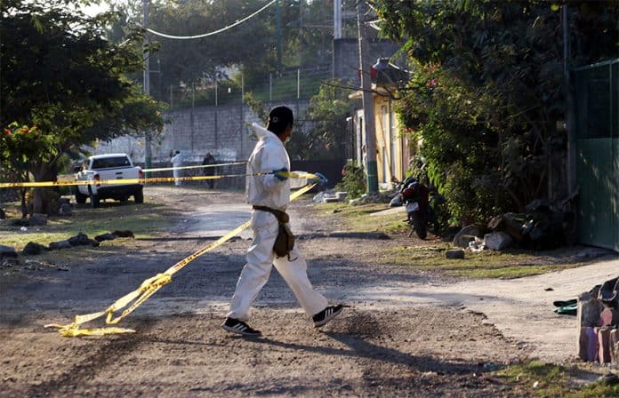 A forensic worker cordons off the scene of a double homicide in Morelos, in December 2021.