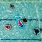 An overhead shot of a pool with several people swimming and floating.