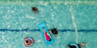 An overhead shot of a pool with several people swimming and floating.