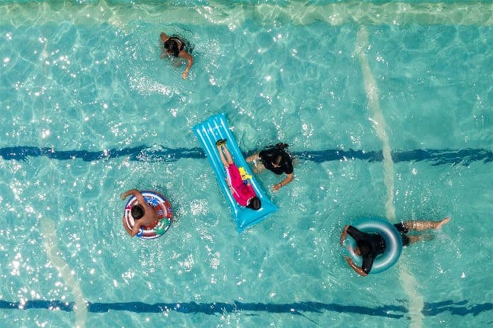 An overhead shot of a pool with several people swimming and floating.
