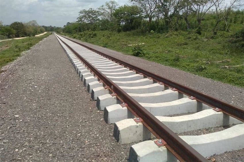 New train tracks run toward the horizon with vegetation in the background.