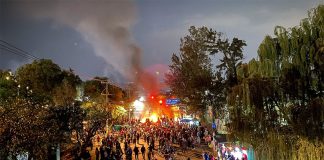 Protesters gather at the blockades Friday evening as the sunsets. Bonfires can be seen blocking the road in the background.