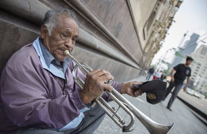 elderly man in mexico city playing the trumpet for money