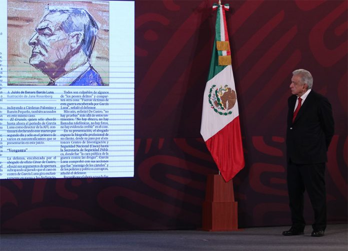 The president stands onstage on the right side, looking toward the left where there is a projected image of a newspaper article including a courtroom sketch of Genaro García Luna.