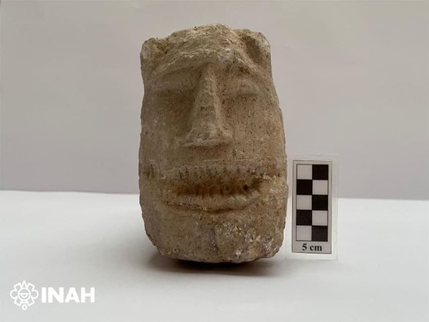 A stone mask or head, approximately 25 cm wide and 40 cm tall, with a ruler for scale.