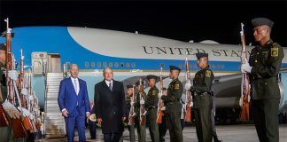 López Obrador and Biden walk away from the Air Force 1 down a red carpet with military cadets standing at attention with rifles on both sides of the walkway.