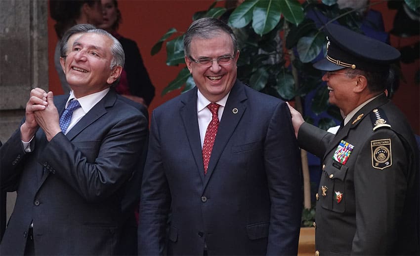Ebrard, center, laughs as a military leader in uniform pats him on the back. On the other side, Interior Minister Adán Augusto López laughs and claps.