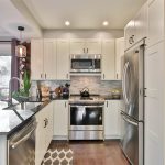 A view of a kitchen with a refrigerator, microwave, stove and other appliances.