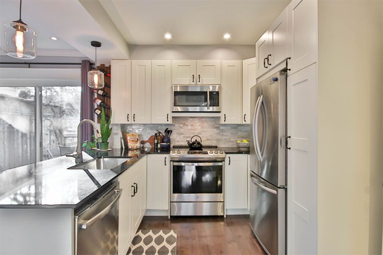 A view of a kitchen with a refrigerator, microwave, stove and other appliances.