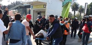 Emergency services push through a crowd to extract injured passengers from the crash on gurneys.