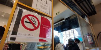 A no smoking sign on a mirrored wall in a pastry shop.