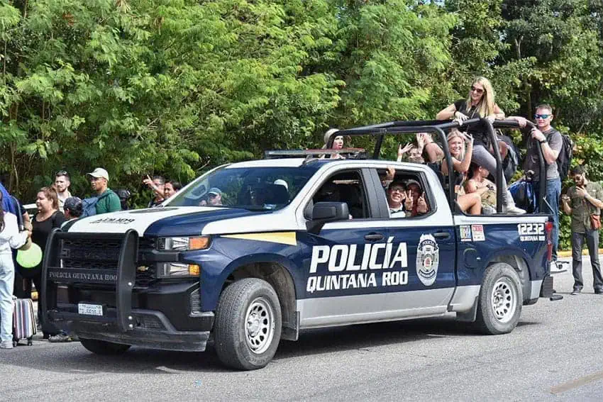 Tourists wave from the back of a Quintana Roo state police vehicle.