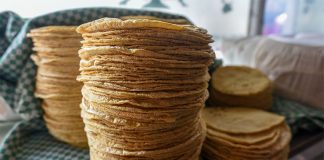 Several stacks of golden tortillas on a white-and-green checkered cloth.