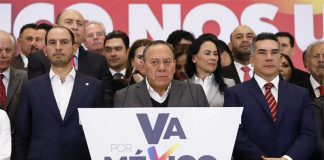 Politicians in suits with frowns and serious expressions stand behind a podium with the Va por México logo.